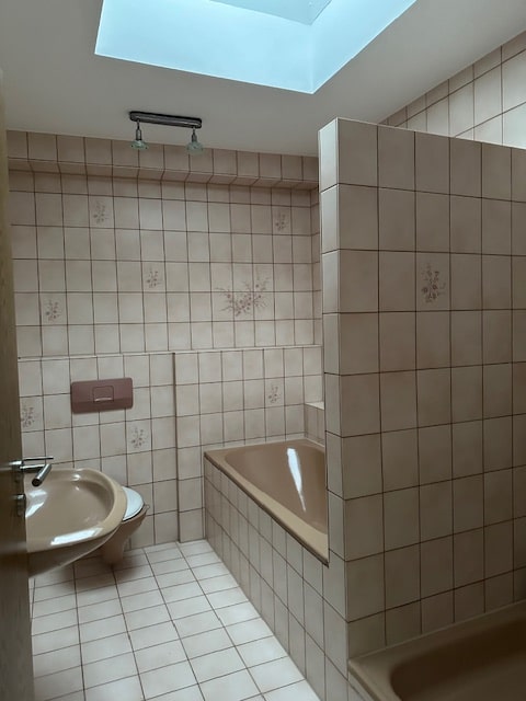 Badezimmer mit Badewanne Toilette und Waschbecken mit Fliesen