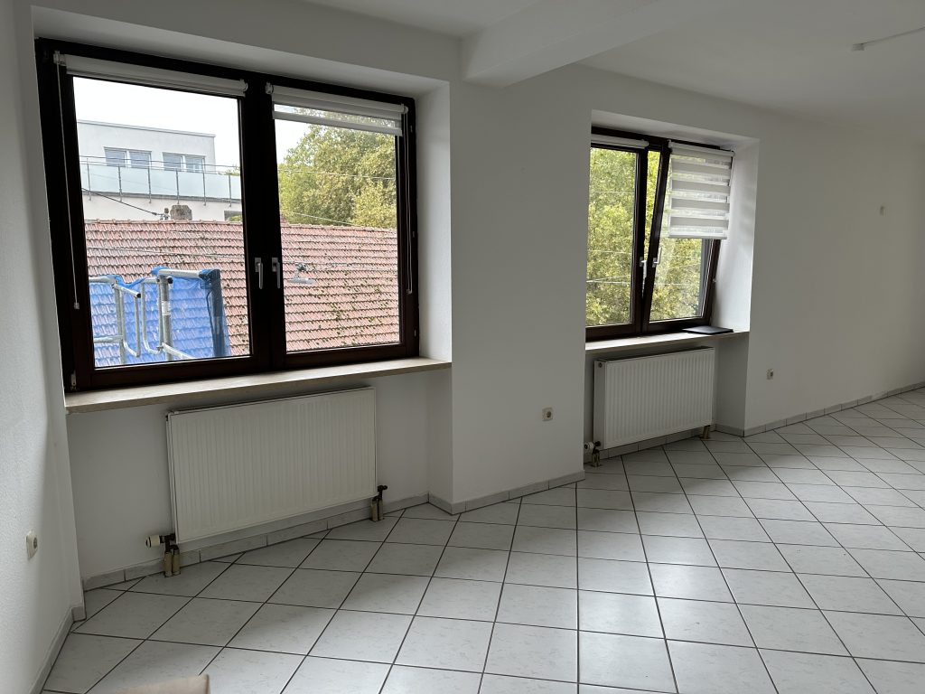 Wohnzimmer mit großem Fenster und Zugang zum Balkon