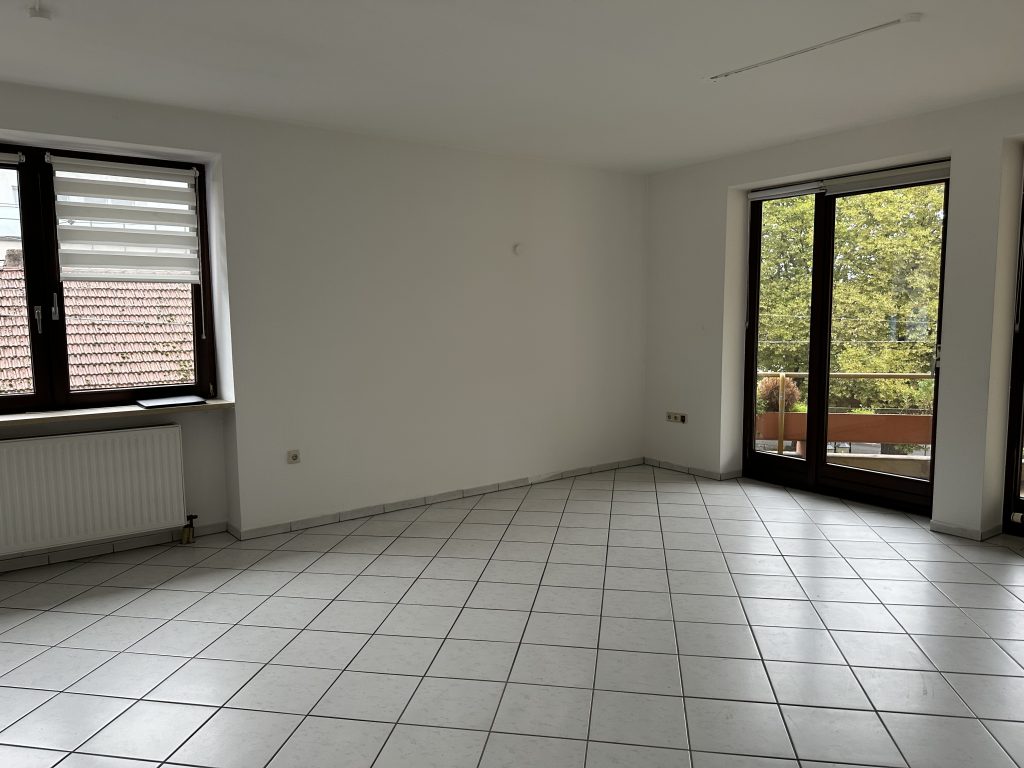 Wohnzimmer mit großem Fenster und Zugang zum Balkon